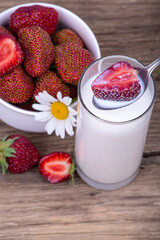 Ripe strawberries in milk, a plate with strawberries on a wooden background, close-up