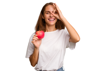 Young caucasian woman holding a red apple isolated excited keeping ok gesture on eye.