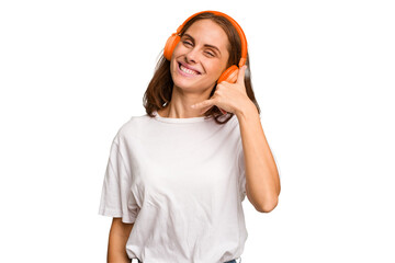 Young caucasian woman listening to music with headphones isolated showing a mobile phone call gesture with fingers.