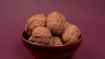 Closeup photo of a walnut seed in wooden bowl. Food that is good for brain and lower risk of heart disease.