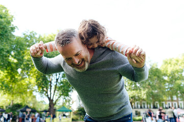 Young father giving a daughter piggyback ride when playing in the park.