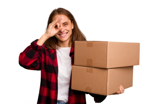 Young caucasian woman moving while picking up a box full of things isolated excited keeping ok gesture on eye.