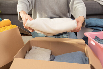 Woman sorting clothes and packing into cardboard box. Donations for charity, help low income...