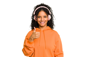 Young Brazilian woman listening to music with headphones isolated smiling and raising thumb up