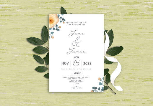 Wedding Invitation or stationery mockup, with beautiful green leaves and ribbon on textured background.