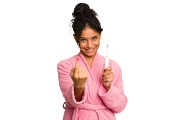Young brazilian woman holding an electric toothbrush isolated pointing with finger at you as if inviting come closer.