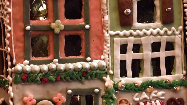 Camera pan movement of a close up gingerbread house in front of a decorated christmas tree