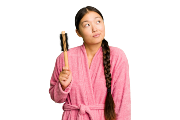 Young asian woman holding an hair comb isolated dreaming of achieving goals and purposes