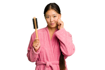 Young asian woman holding an hair comb isolated pointing temple with finger, thinking, focused on a task.