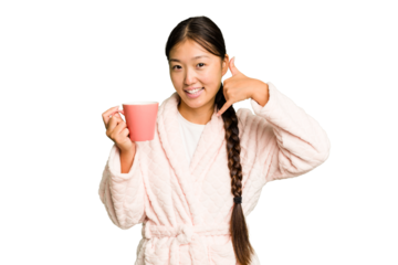 Young asian woman wearing a pajama holding a cup isolated showing a mobile phone call gesture with fingers.