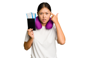 Young asian woman with inflatable travel pillow on her neck holding passport isolated showing a disappointment gesture with forefinger.