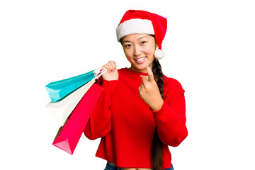Young asian woman shopping a christmas presents isolated Young asian woman shopping a christmas presents isolated pointing with finger at you as if inviting come closer.