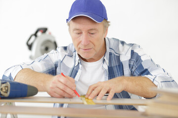 craftsman measuring wood with ruler and pen for cutting