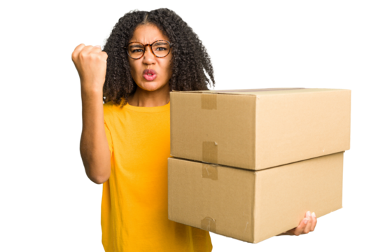Young african american woman moving to other house while picking up a box full of things isolated showing fist to camera, aggressive facial expression.