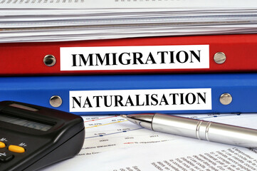 Dossiers immigration et naturalisation empilés sur un bureau en gros plan
