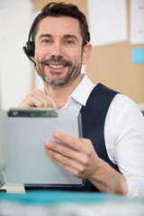 smiling man wearing headset and holding a clipboard