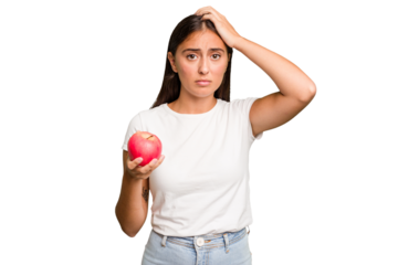 Young caucasian woman holding a red apple isolated being shocked, she has remembered important meeting.