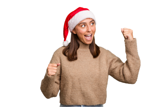 Young caucasian woman celebrating christmas wearing a santa hat isolated raising fist after a victory, winner concept. - Powered by Adobe