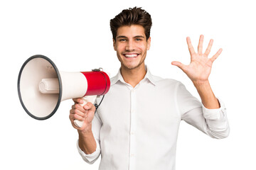 Young caucasian man holding megaphone isolated smiling cheerful showing number five with fingers.