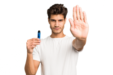 Young caucasian man holding an electronic cigarette isolated standing with outstretched hand showing stop sign, preventing you.