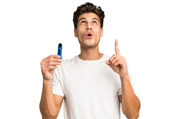 Young caucasian man holding an electronic cigarette isolated pointing upside with opened mouth.