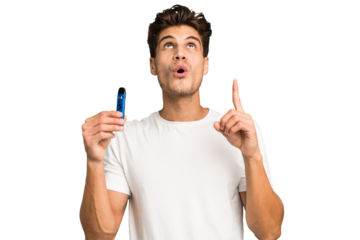 Young caucasian man holding an electronic cigarette isolated pointing upside with opened mouth.