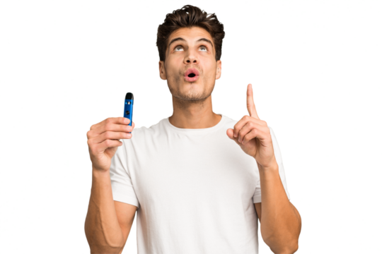 Young caucasian man holding an electronic cigarette isolated pointing upside with opened mouth.