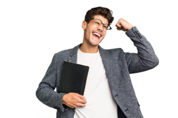 Young teacher caucasian man holding a book isolated raising fist after a victory, winner concept.