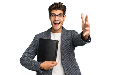 Young teacher caucasian man holding a book isolated receiving a pleasant surprise, excited and...