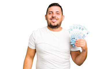 Young caucasian man holding a banknotes isolated happy, smiling and cheerful.