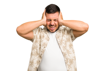 Young caucasian man isolated covering ears with hands trying not to hear too loud sound.