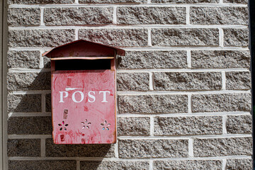 red royal mail post box in front of brick wall