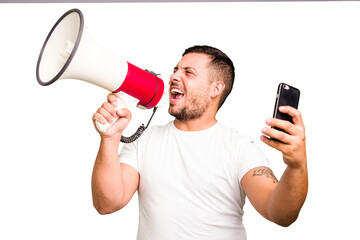 Young caucasian man holding megaphone in streaming with a phone isolated