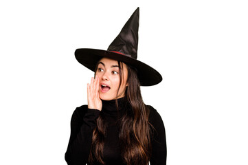 Fototapeta premium Young caucasian woman dressed as a witch isolated on green chroma background shouting and holding palm near opened mouth.