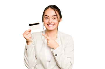 Young caucasian woman holding a credit card isolated on green chroma background smiling and pointing aside, showing something at blank space.