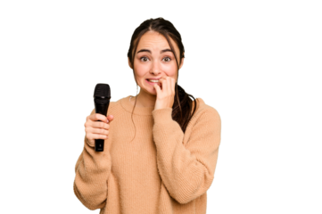 Young caucasian singer woman isolated on green chroma background biting fingernails, nervous and very anxious.