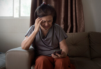 Fototapeta premium old asian woman looking mobile phone feel headache and suffering from mental health