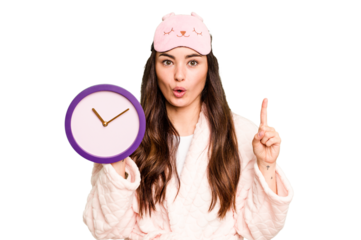 Young caucasian woman holding a clock wearing a pajama isolated on green chroma background having some great idea, concept of creativity.