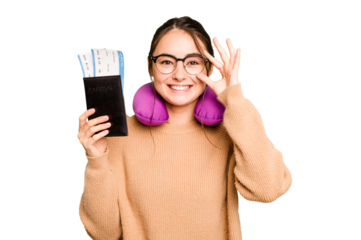 Young caucasian woman with inflatable travel pillow holding passport isolated on green chroma background excited keeping ok gesture on eye.