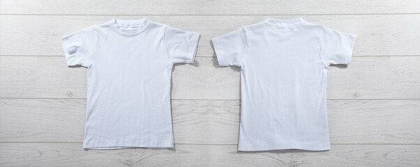Front and back views on boys t-shirts on white wooden desk background. Mockup for design closeup