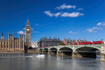 Fototapeta na wymiar Big Ben with red buses on bridge over Thames river with boat in London, England, UK