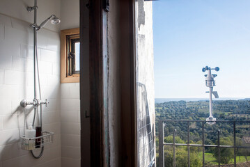Lavabo con ducha de diseño en la mitad de la fotografía y balcón con vistas en la mitad derecha...