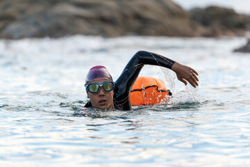 Woman swimming in open water with wetsuit and buoy