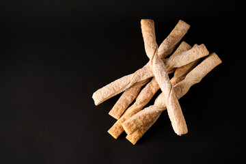 Puff pastry sticks with cinnamon on black background