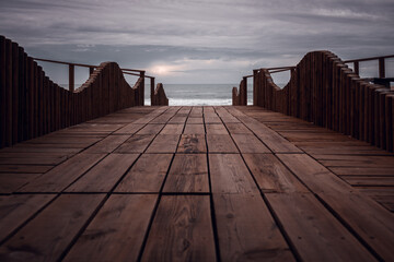 Long wooden pier boardwalk in Quiaios beach with low viewpoint perspective leading to the Atlantic...