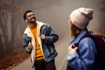 Couple spending time together walking on forest road on a foggy morning.