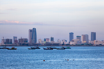 Fototapeta premium People swimming at Nguyen Trai Beach in Da Nang at dusk.