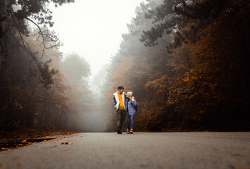 Couple spending time together walking on forest road on a foggy morning.