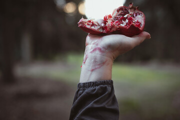 Close up mashed up pomegranate concept photo. Red juicy fruit. Front view photography with female...