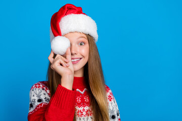 Photo of charming positive lady teenager arm hold white pompon red headwear good mood empty space isolated on blue color background